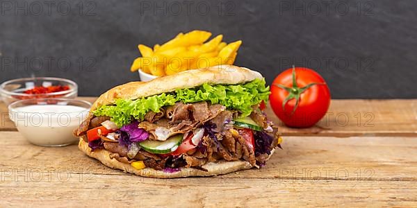 Doener Kebab Doner Kebap fast food meal in pita bread menu with fries Panorama on wooden board with text free space Copyspace in Stuttgart