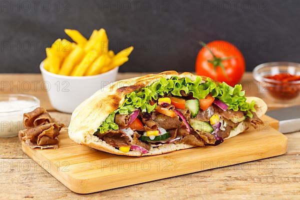 Doener Kebab Doner Kebap half fast food meal in pita bread with fries on wooden board in Stuttgart