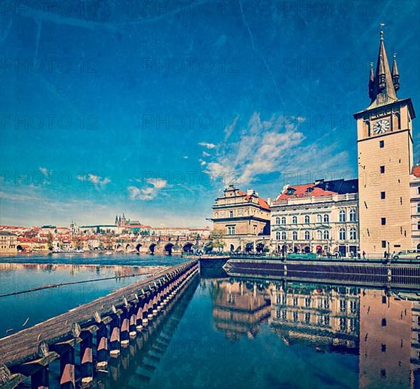 Vintage retro hipster style travel image of Prague Stare Mesto embankment view from Charles bridge with grunge texture overlaid. Prague