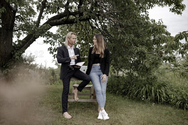 Man and woman talking on a wooden table in nature