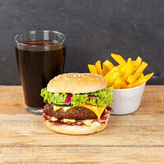 Hamburger Cheeseburger fast food meal menu with fries and cola drink on wooden board square in Stuttgart