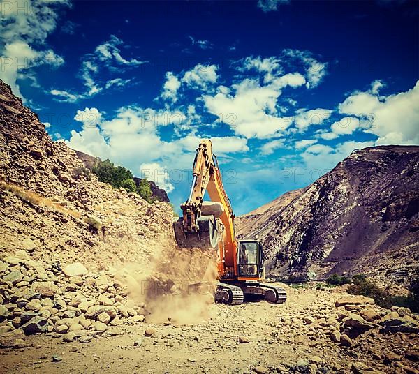 Vintage retro effect filtered hipster style travel image of Excavator doing road construction in Himalayas. Ladakh