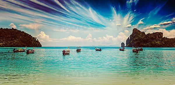 Vintage retro effect filtered hipster style travel image of long tail boat on beach on sunset on ebb. Thailand
