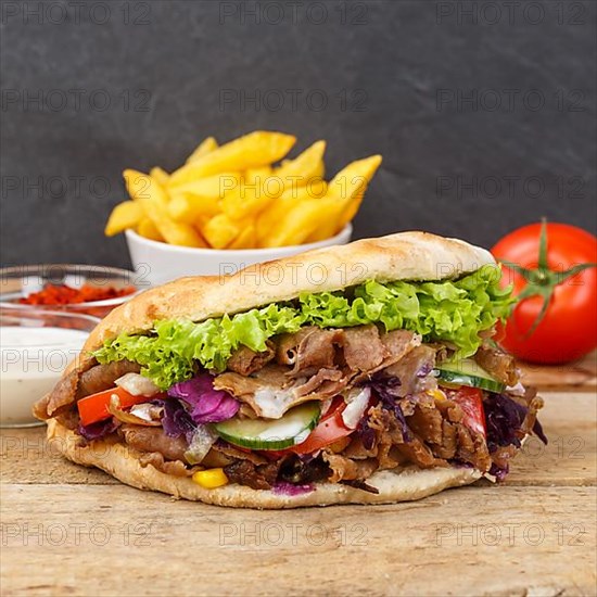 Doener Kebab Doner Kebap fast food meal in pita bread with fries on wooden board square in Stuttgart