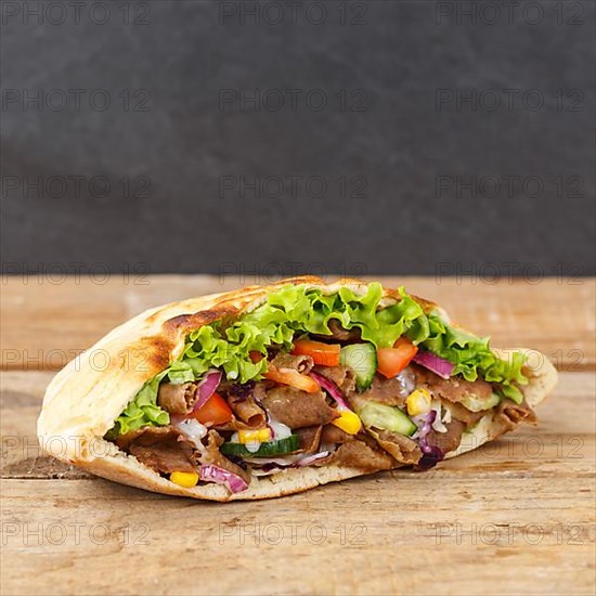 Doener Kebab Doner Kebap fast food food in pita bread on wooden board square copy space Copyspace in Stuttgart