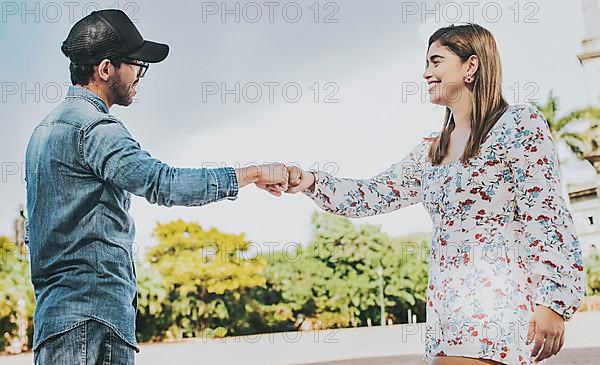 A guy and girl shaking hands on the street. Two young smiling teenagers shaking hands in the street. Concept of man and woman shaking hands on the street