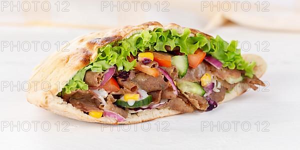 Doener Kebab Doner Kebap half fast food meal in pita bread panorama on wooden board in Stuttgart