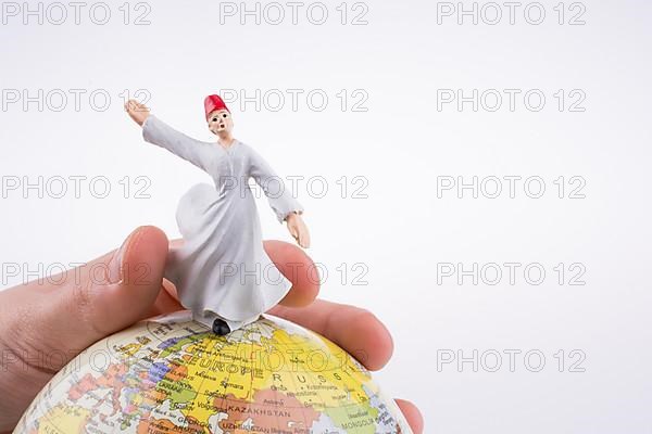 Hand holding a Sufi Dervis on a globe