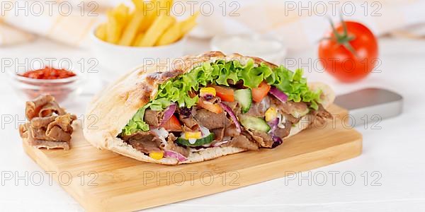 Doener Kebab Doner Kebap half fast food meal in pita bread with fries on wooden board Panorama in Stuttgart