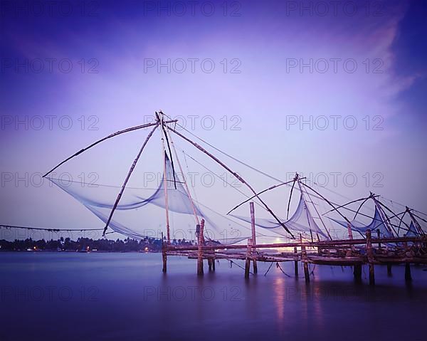 Vintage retro hipster style travel image of Kochi chinese fishnets on sunset. Fort Kochin