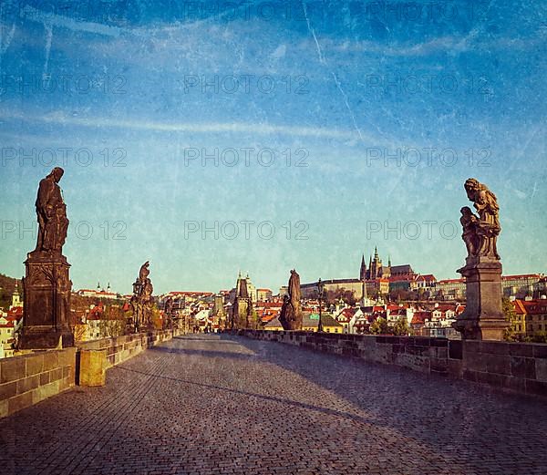 Vintage retro hipster style travel image of Charles bridge and Prague castle in the early morning with grunge texture overlaid. Prague