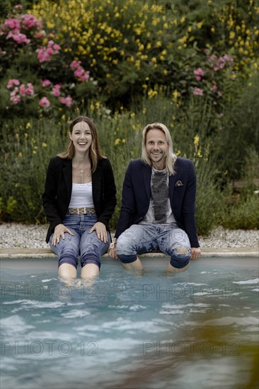 Laughing couple sitting by the poolside