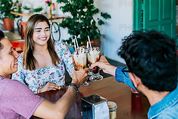 Three smiling best friends meeting and toasting in a coffee shop