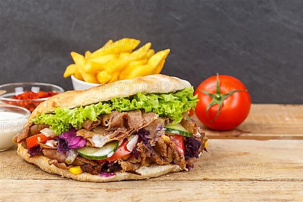 Doener Kebab Doner Kebap fast food meal in pita bread menu with fries on wooden board with text free space copyspace in Stuttgart