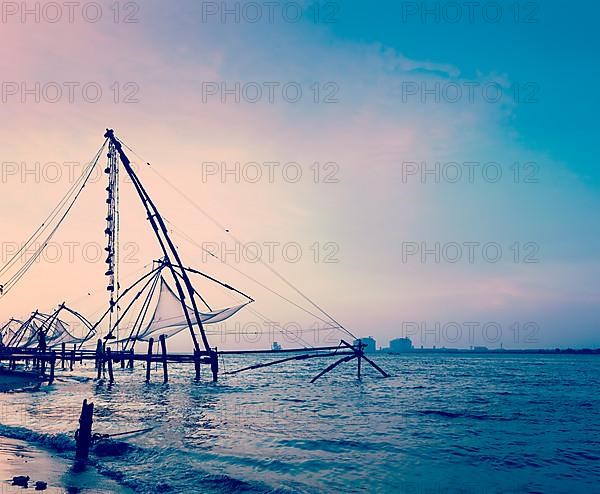 Vintage retro hipster style travel image of Kochi chinese fishnets on sunset. Fort Kochin