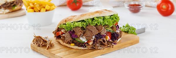 Doener Kebab Doner Kebap fast food meal in pita bread menu with fries on kitchen board Panorama in Stuttgart