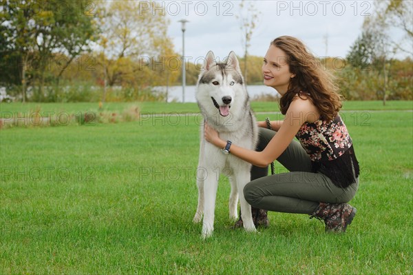 Girl playing with husky dog in city park. Training the dog