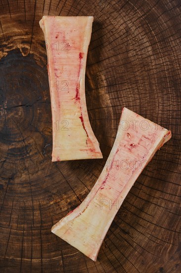 Overhead closeup view of large beef bone marrow chopped on half on wooden stump