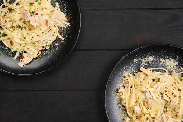 Top view of two plate with pasta with ham and mushrooms