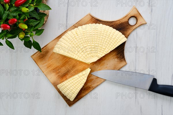 Fresh Adyghe cheese cut on slices on wooden cutting board