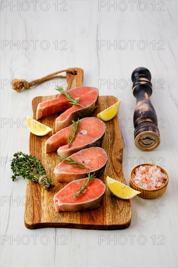 Overhead view of raw trout steaks on wooden cutting board ready for cooking