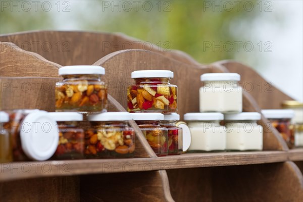 Nuts and honey in small jars on shelf