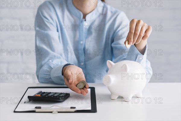 Businesswoman showing coins with white piggybank desk