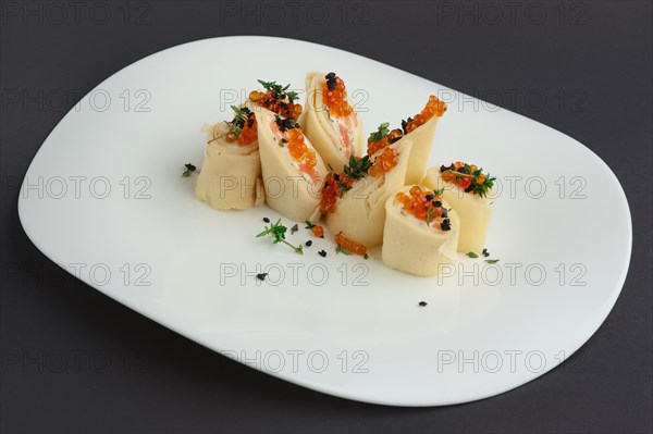 Pancakes with salmon and caviar on big white plate