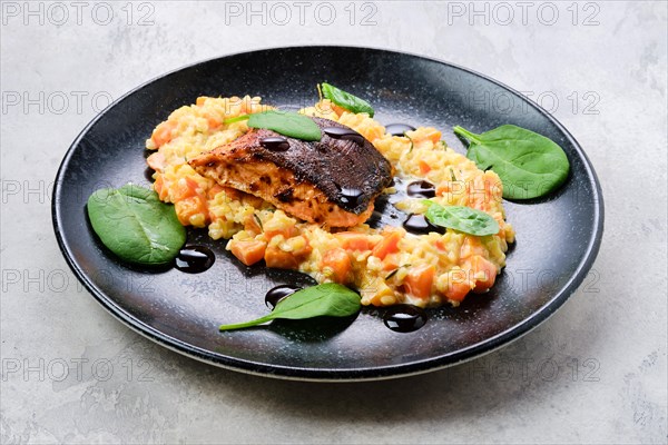Fried salmon steak served with bulgur and sweet potato on a plate
