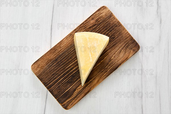 Top view of triangular piece of goat cheese on wooden cutting board
