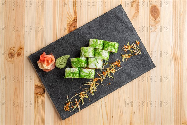 Set of rolls with wasabi and pickled ginger on stone serving board