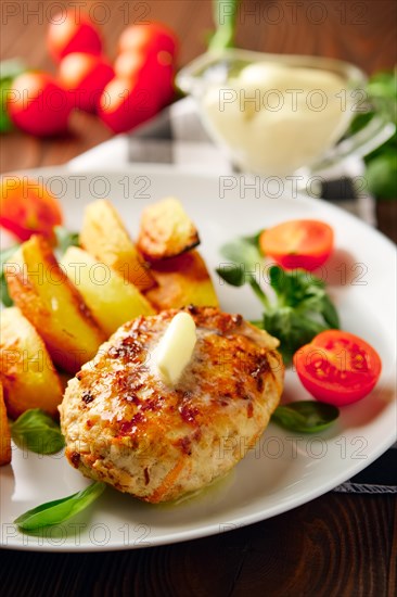 Fried chicken cutlet with potato slices served with tomato cherry and corn salad. Traditional belorussian food