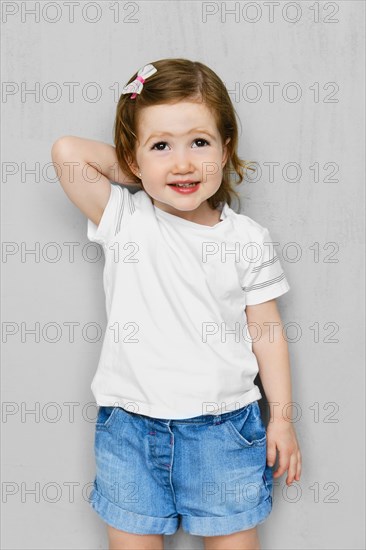 Two years old girl in white t-short and jeans shorts posing in studio