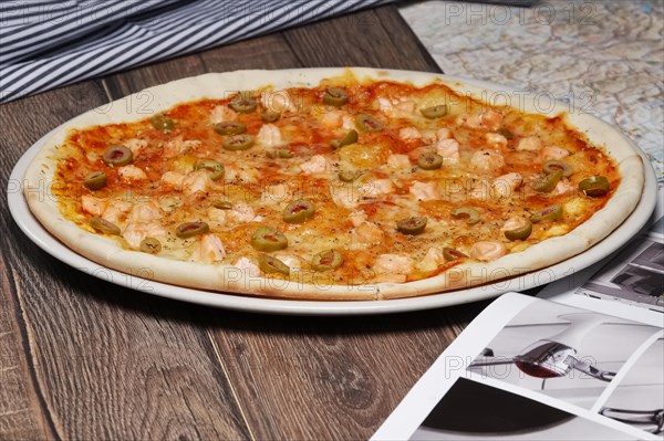 Pizza with salmon and olives on wooden table