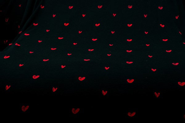 Black fabric background with red hearts shapes