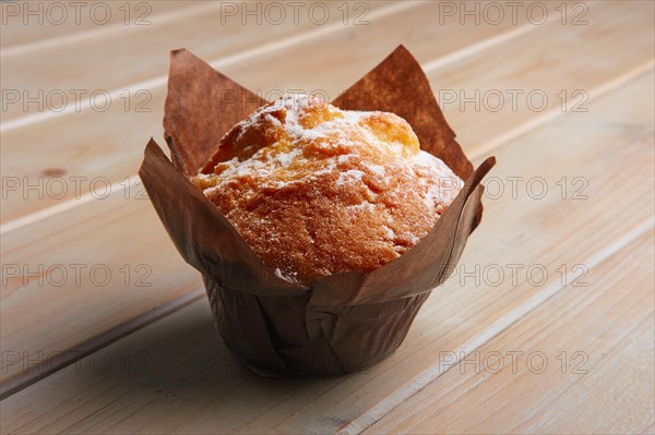 Fresh muffin with powdered sugar in paper wrapper