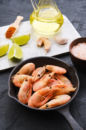 Cast iron skillet with steamed unpeeled shrimps with spice