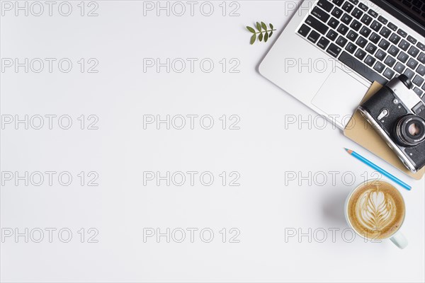 Old camera notebook laptop with blue pencil cup cappuccino white background