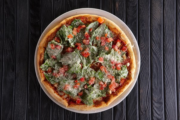 Top view of pizza with ham and green salad leaves arugula