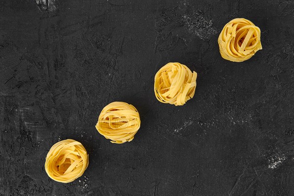 Top view of raw tagliatelle on black background