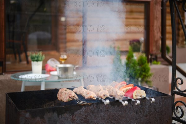 Pork meat and champignons on skewer over the charcoal in barbecue