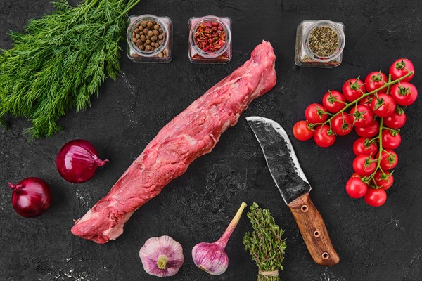 Top view of raw fresh pork fillet with spice on black background