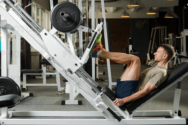 Young athlete pushing up barbell in gym. Fitness workout