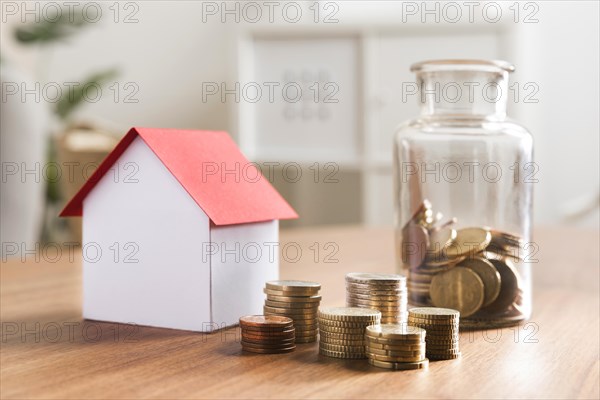 Miniature bank with coins stacks jar beside