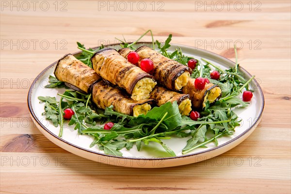 Eggplant rolls stuffed with soft cheese and garlic decorated with arugula and cranberry