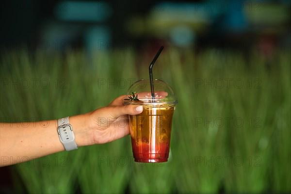 Hand with espresso tonic iced drink in plastic take away cup