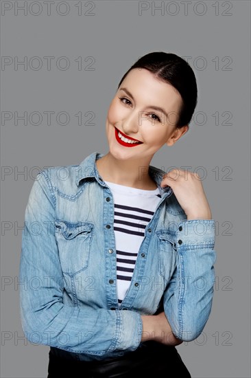 Pretty smiling fashion model in jeans shirt with tan makeup and red mat lips