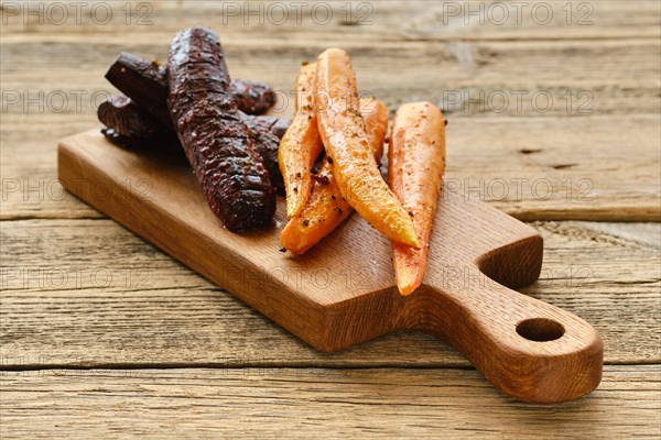 Baked carrot and beetroot with salt and pepper on wooden board