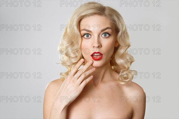 Surprised girl with curly blonde hair and wide opened eyes