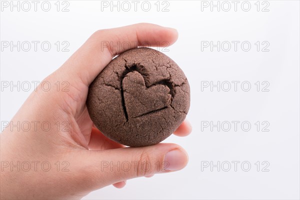 Hand holding a heart patterned chocolate cookie on a white background